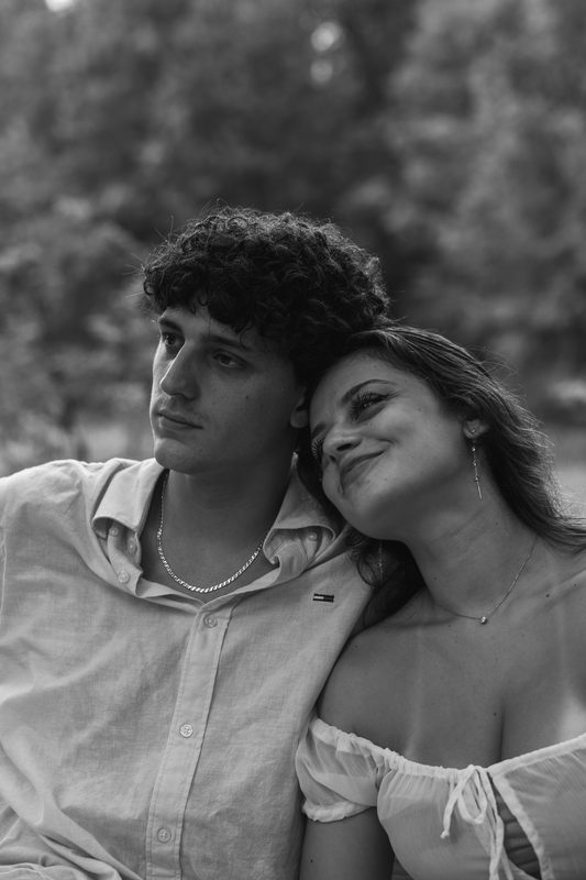 Bianco e nero: lei appoggia il viso sulla spalla di lui e sorride, lui guarda lontano