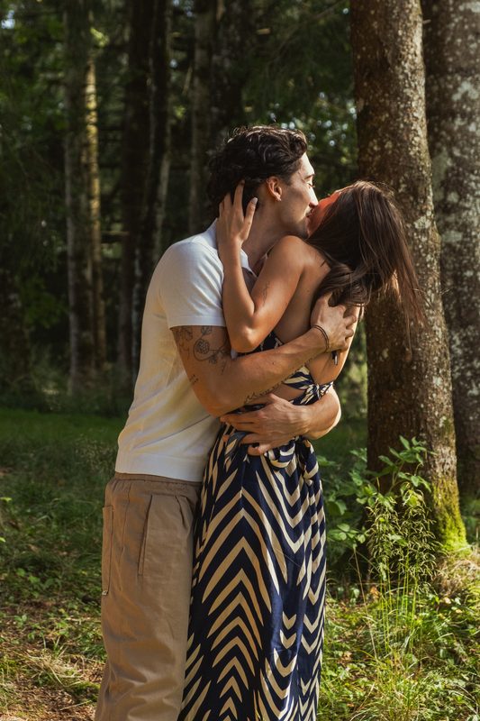 Bacio accanto al tronco di un abete, lei rovescia la testa all'indietro
