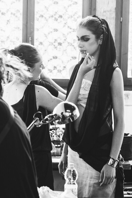 Bianco e nero: backstage di una sfilata, truccatrice al lavoro su una modella