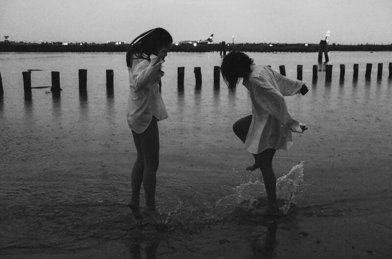 Bianco e nero: due bambine giocano nell'acqua bassa della laguna