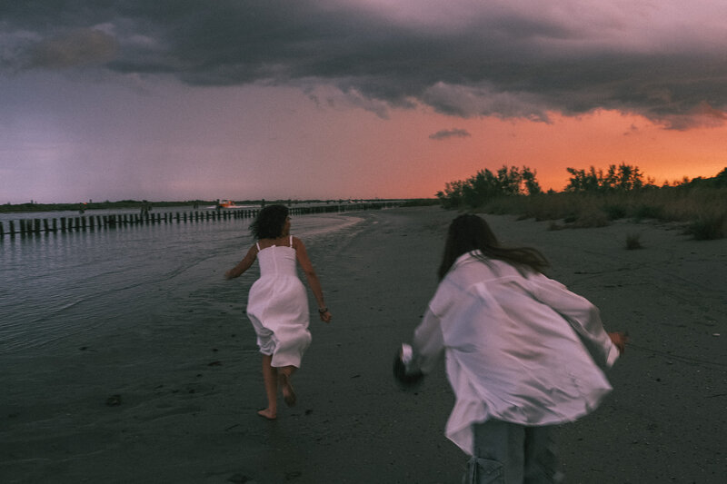 Due bambine corrono sulla spiaggia al tramonto